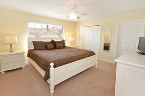 A bedroom with a bed, nightstands, a TV, a wardrobe, and a ceiling fan. - Paradise Palms - Ocean 241 - 5745 (Kissimmee)
