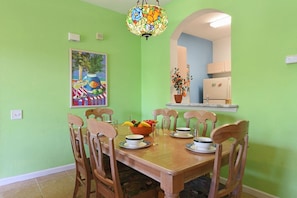 A dining area with a wooden table, chairs, a bowl of fruit, and a painting on the wall. - Windsor Palms - 35432 (Kissimmee)
