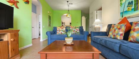 A living room with a wooden coffee table, blue sofas, and a television.