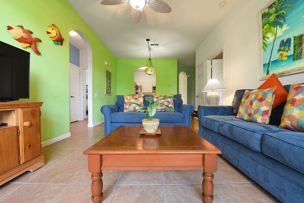 A living room with a wooden coffee table, blue sofas, and a television. - Windsor Palms - 35432 (Kissimmee)
