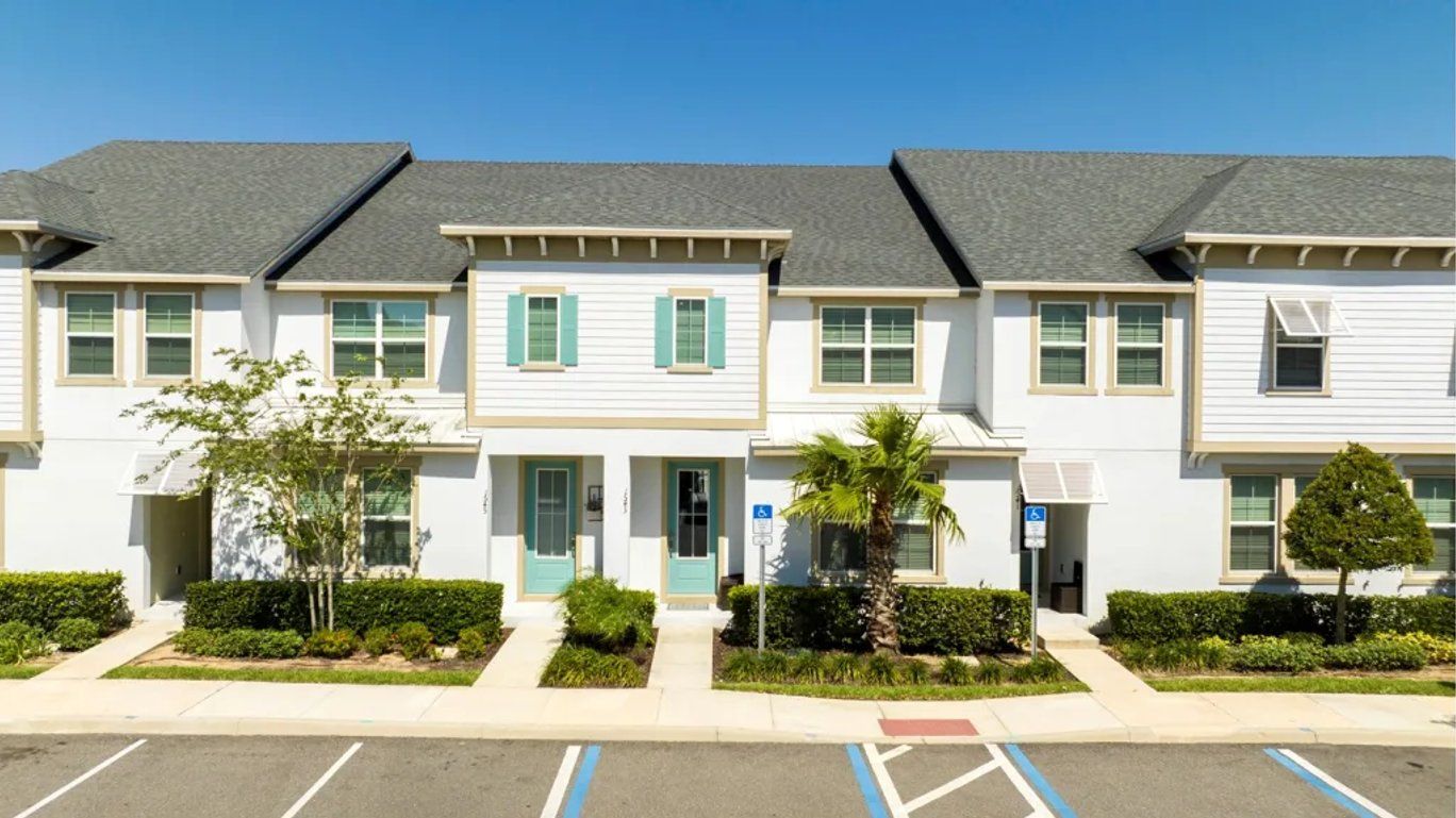A row of townhouses with a parking lot in front.