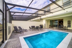 A swimming pool with lounge chairs and a covered patio area. - Windsor at Westside - 28836 (Kissimmee)