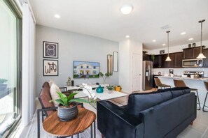 A modern kitchen with dark cabinets, a microwave, and a refrigerator. - Windsor at Westside - 28836 (Kissimmee)