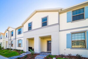 A row of townhouses with a front porch, a door, and a mailbox. - Windsor at Westside - 28836 (Kissimmee)