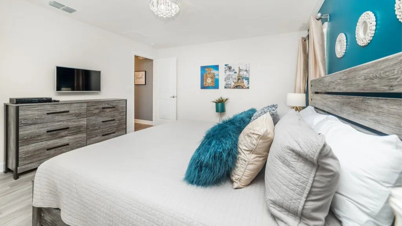 Een slaapkamer met een bed, een televisie, een dressoir en wanddecoratie.