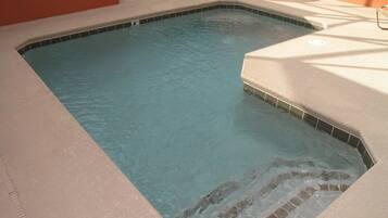Une piscine avec un bord carrelé et une zone plus profonde.