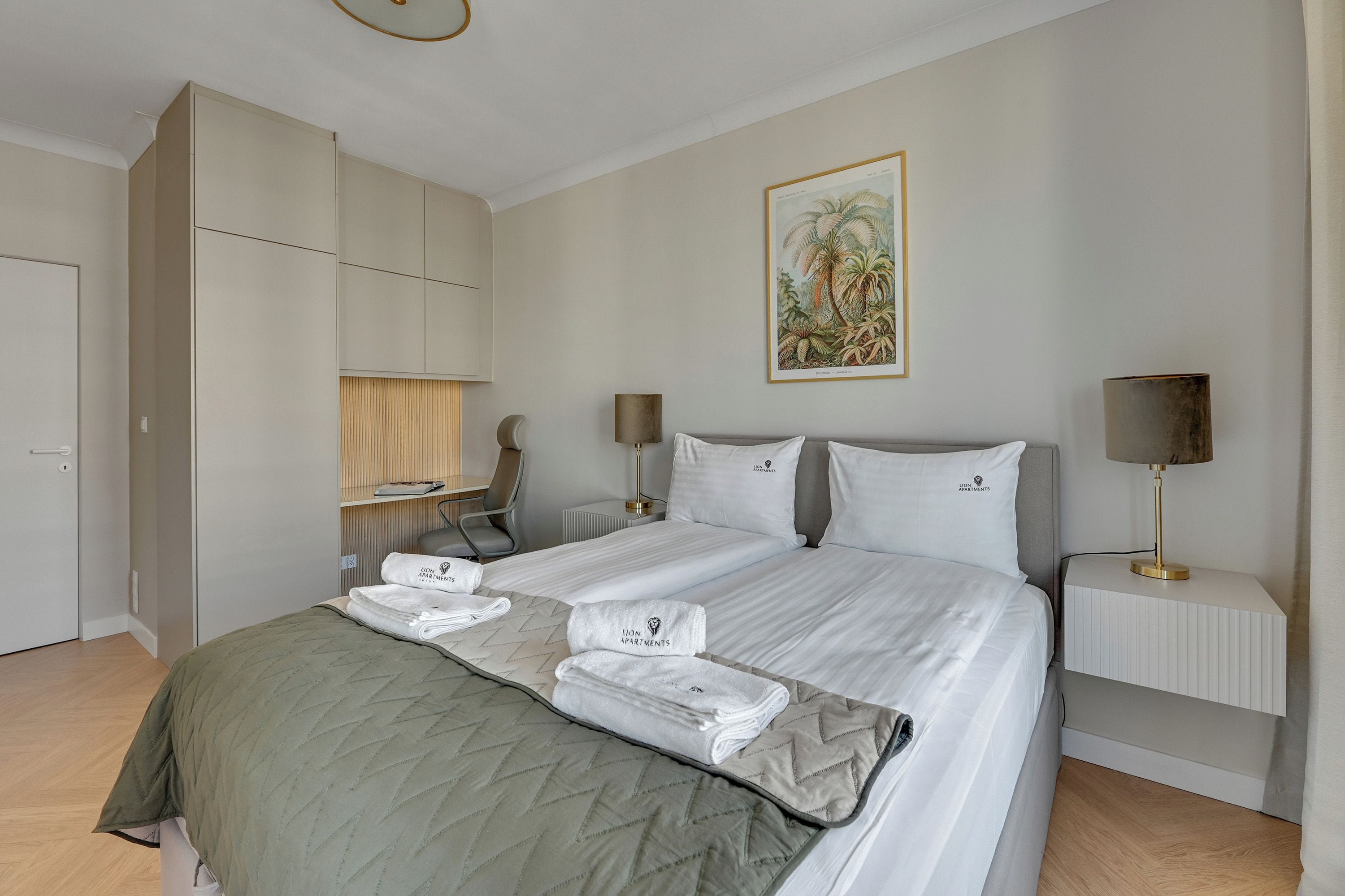 Habitación de hotel con una cama, un escritorio, una silla, una lámpara y un cuadro en la pared.