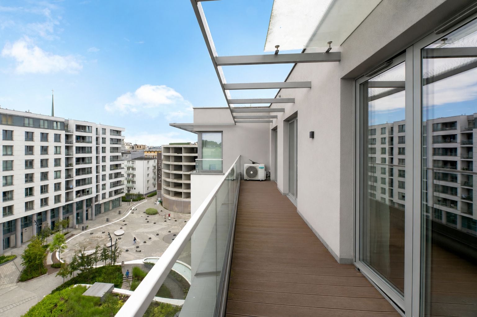 A modern balcony with a view of a cityscape, a covered walkway, and a building with a cross on top.