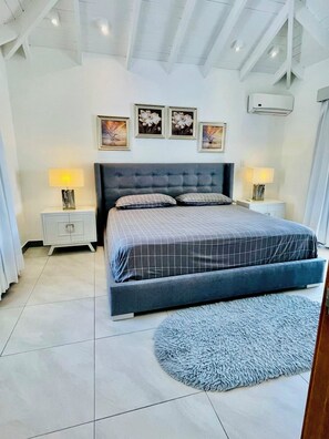 A bedroom with a large bed, two bedside tables with lamps, a ceiling fan, and three wall-mounted pictures. - Sun, Pool & Sand! 3BR Family Villa Near the Beach (Cabarete)