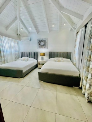 A hotel room with two beds, a nightstand, a wall-mounted air conditioner, and a ceiling fan. - Sun, Pool & Sand! 3BR Family Villa Near the Beach (Cabarete)