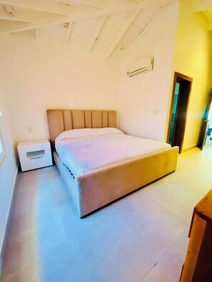 Une chambre à coucher avec un lit, une table de chevet et une porte donnant sur une autre pièce.