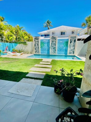 A backyard with a swimming pool, a paved patio, and a grassy area with stepping stones. - Sun, Pool & Sand! 3BR Family Villa Near the Beach (Cabarete)
