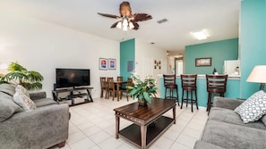 A living room with a television, sofas, a coffee table, and a ceiling fan. - Windsor Palms - 6279 (Kissimmee)