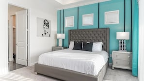 A bedroom with a large bed, two bedside tables, a door, and a wall with a picture. - Storey Lake - 7330 (Kissimmee)