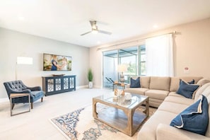 A living room with a sofa, armchair, coffee table, and artwork on the wall. - Reunion - 7689 (Kissimmee)