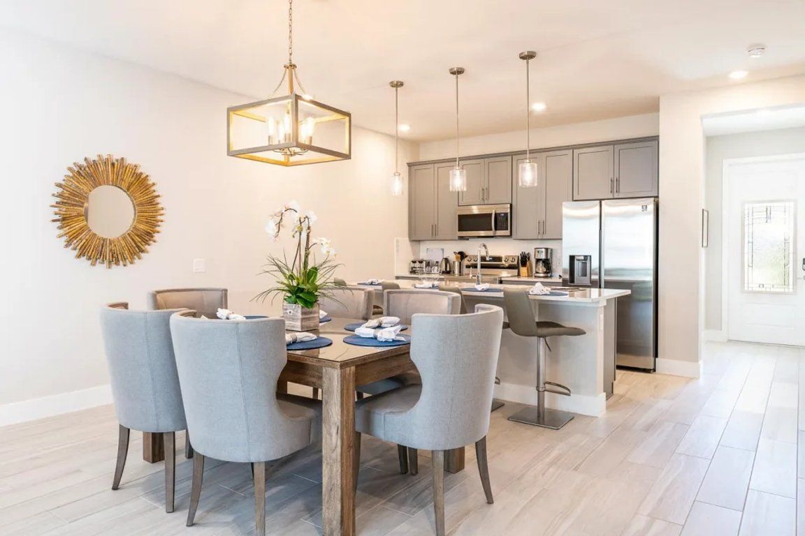 A modern kitchen with grey cabinets, stainless steel appliances, and pendant lighting.