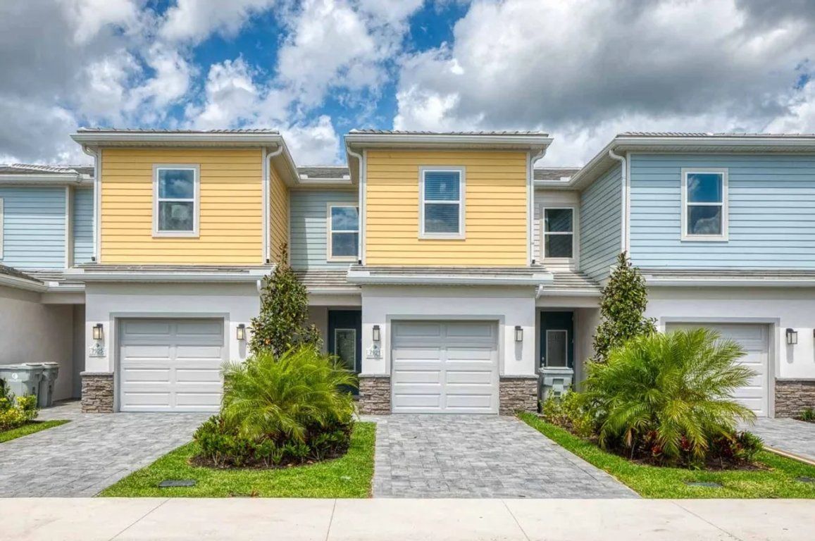 Une rangée de maisons de ville, chacune dotée d’un garage individuel et d’une allée pavée.