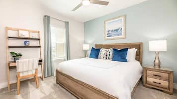 Une chambre à coucher comprenant un lit, des tables de chevet, un bureau, une chaise, un ventilateur de plafond et une fenêtre avec des rideaux.
