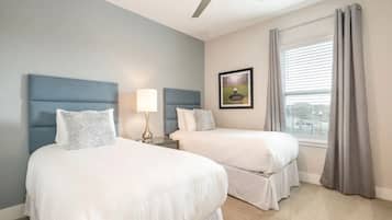 Habitación de hotel con dos camas, un ventilador de techo, una ventana con cortinas y un cuadro en la pared.