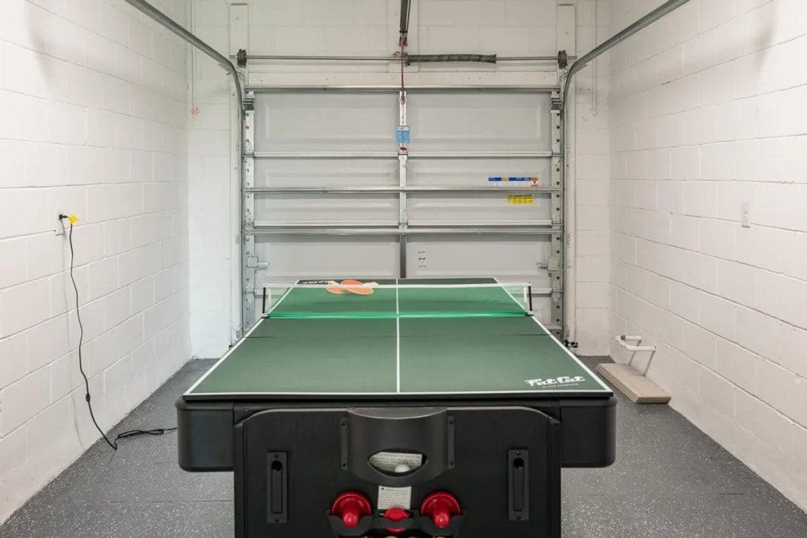 A ping pong table in a room with white brick walls and a metal door.