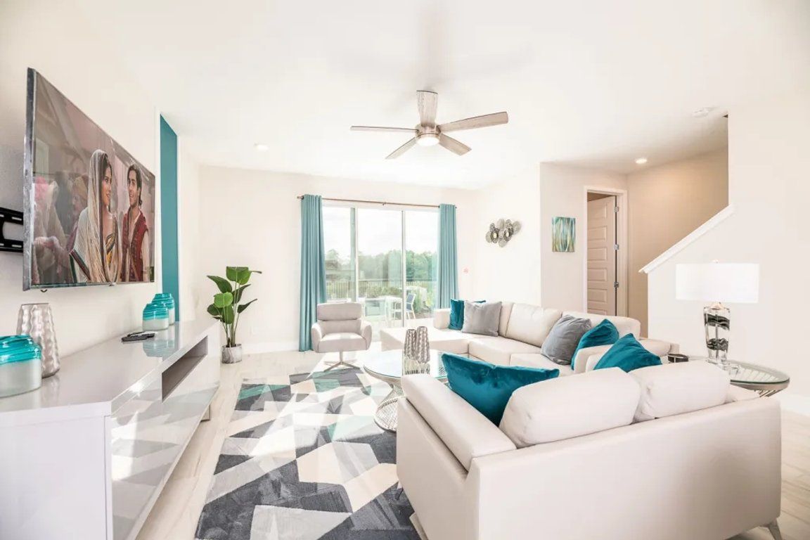 Un salon moderne avec un canapé blanc, une table basse et un ventilateur de plafond.