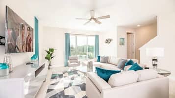 Un salon moderne avec un canapé blanc, une table basse et un ventilateur de plafond.