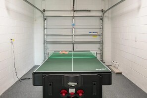 Un tavolo da ping pong in una stanza con pareti in mattoni bianchi e una porta metallica.