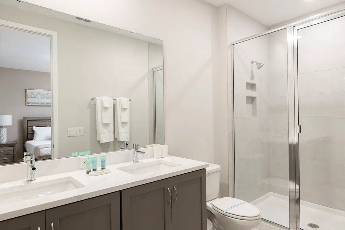 Un baño moderno con lavamanos doble, inodoro y ducha con mampara de vidrio.