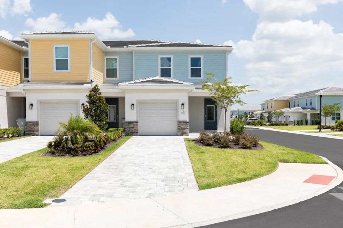 A residential area with two-story houses, a paved driveway, and a well-maintained lawn.