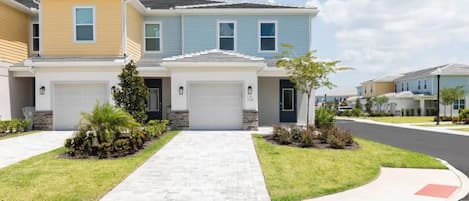 A residential area with two-story houses, a paved driveway, and a well-maintained lawn.