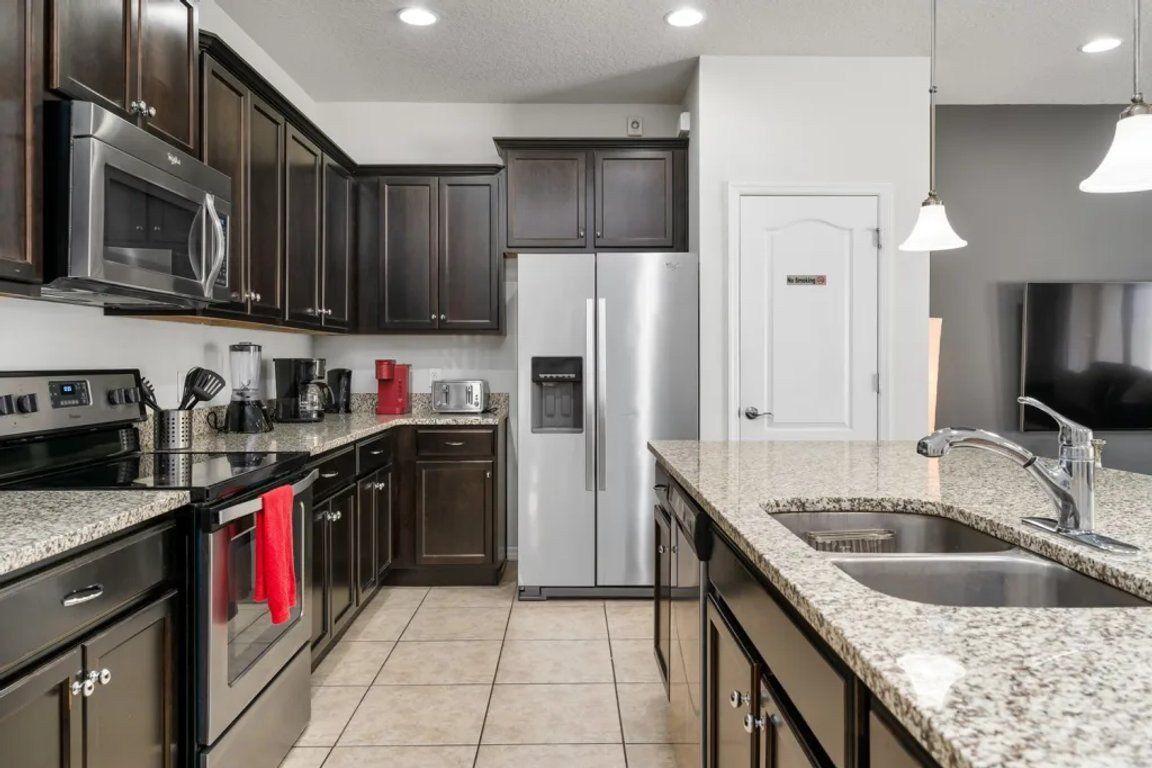 A modern kitchen with stainless steel appliances, dark cabinetry, and a granite countertop.