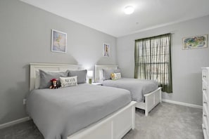 A bedroom with two beds, a dresser, and a window with curtains. - Windsor Hills - 11510 (Kissimmee)