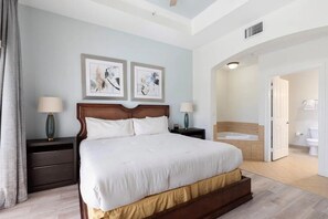 Habitación de hotel con una cama grande, dos mesitas de noche, un cabecero y una obra de arte en la pared.
