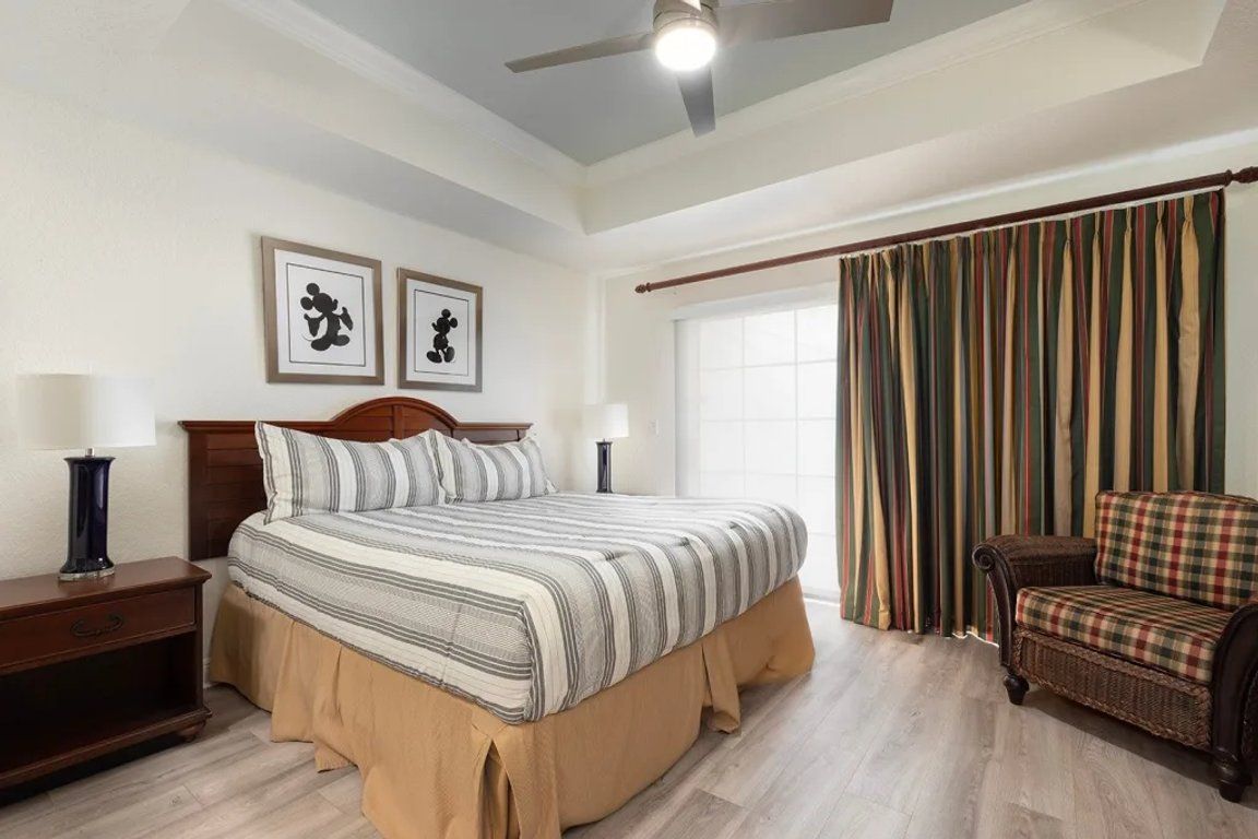 Une chambre à coucher avec un lit, une table de chevet, une chaise et des rideaux.