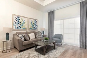 Una sala de estar con sofá, sillón, mesa de centro y una obra de arte en la pared.