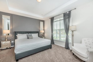 A bedroom with a large bed, bedside tables, a chair, and a window with curtains. - Solara Resort - 25528 (Kissimmee)