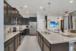 A modern kitchen with dark cabinetry, granite countertops, stainless steel appliances, and pendant lighting. - Windsor Island - 25602 (Davenport)