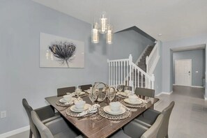 A dining area with a wooden table set for six, a staircase, and a white door. - Windsor Island - 25602 (Davenport)