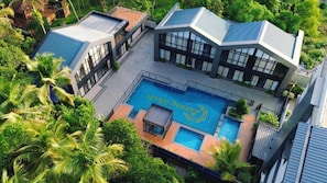 A modern building with a swimming pool surrounded by lush greenery.