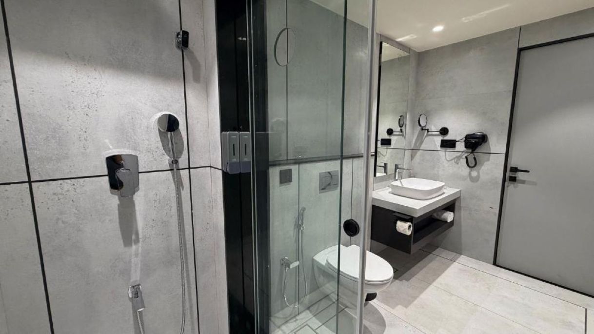 Een moderne badkamer met een douchecabine van glas, een toilet en een wastafel met spiegel.