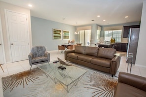 A modern living room with a glass coffee table, a brown leather sofa, and a patterned rug. - Solara Resort - 25995 (Kissimmee)
