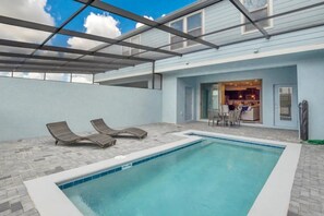 A swimming pool with lounge chairs and a covered patio area. - Windsor at Westside - 26139 (Kissimmee)