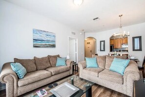 A living room with two sofas, a glass coffee table, and a painting on the wall. - Vista Cay - 26552 (Orlando)