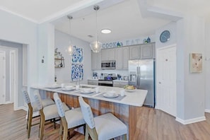 A modern kitchen with a central island, stainless steel appliances, and a dining area with chairs. - Vista Cay - 27376 (Orlando)