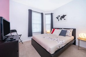 Un dormitorio con cama, escritorio, silla, televisión y un mapa mundial en la pared.