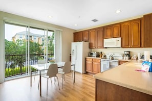 Una cocina moderna con armarios de madera, un refrigerador, un microondas y un comedor con mesa y sillas.