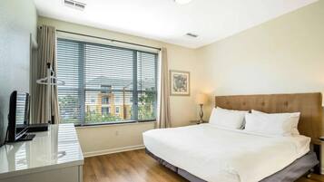 Una habitación de hotel con una cama, un escritorio, una lámpara y una ventana con persianas.