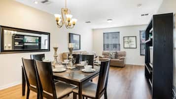Un comedor con una mesa y sillas de madera, un candelabro y un espejo grande en la pared.