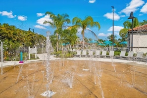 A water fountain with multiple jets, surrounded by palm trees and a clear blue sky. - Vista Cay - 28789 (Orlando)