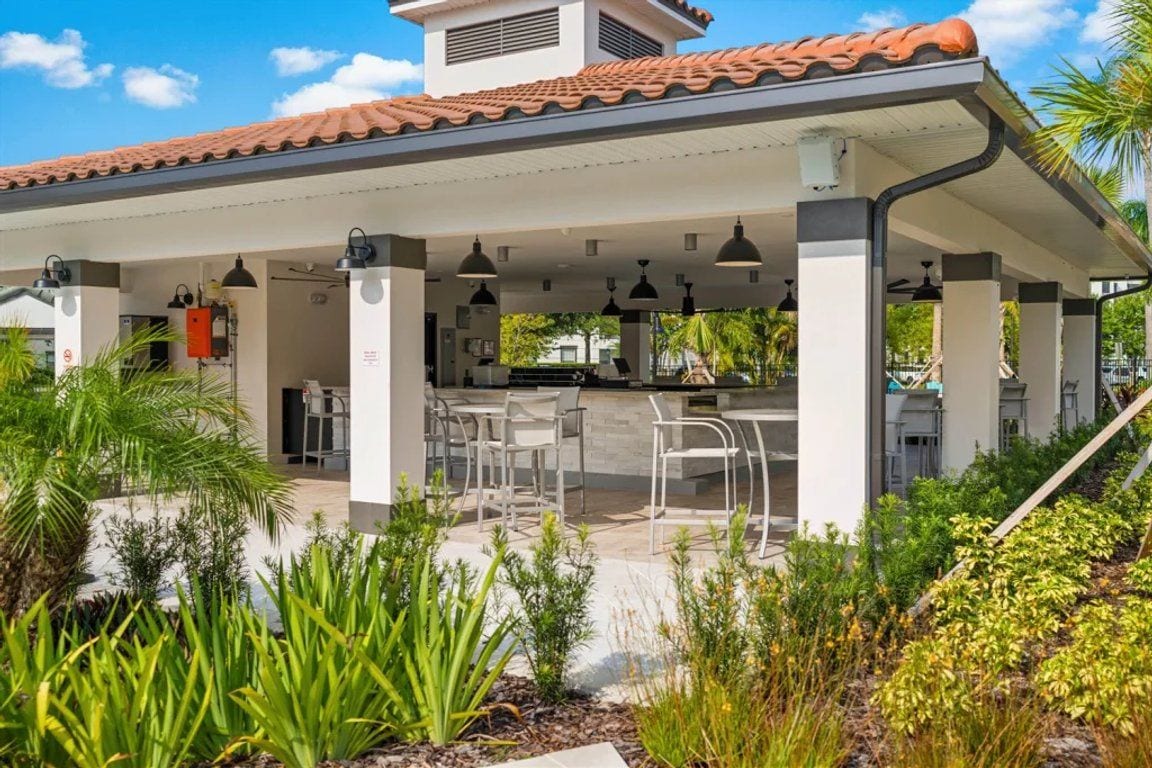 An outdoor patio area with a covered seating area, a water feature, and a variety of plants.